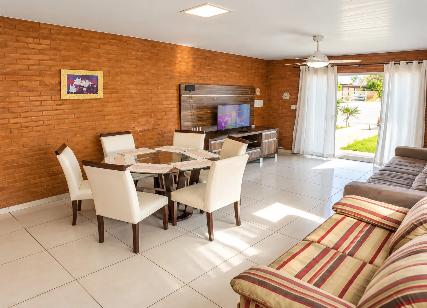 Sala da Casa de 2 Quartos com parede de tijolos aparentes, mesa de jantar e sofás